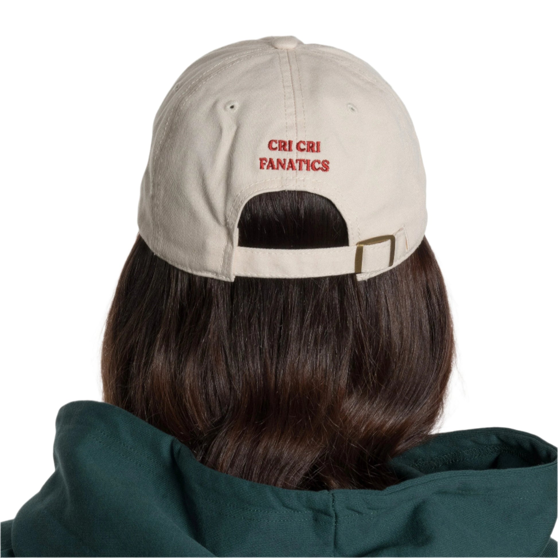 Parte trasera de la gorra en color beige con la frase 'cri cri fanatics' bordado en color rojo, justo encima de la correa ajustable con deslizador en metal.