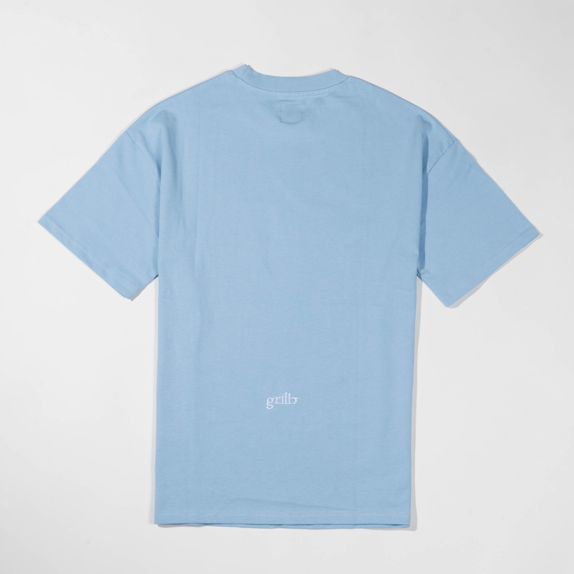 Parte trasera de la camiseta de manga corta azul celeste. Logo bordado en blanco y situado en la parte inferior de la camiseta. Corte oversized.